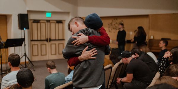 Two people warmly embracing in a crowded room.