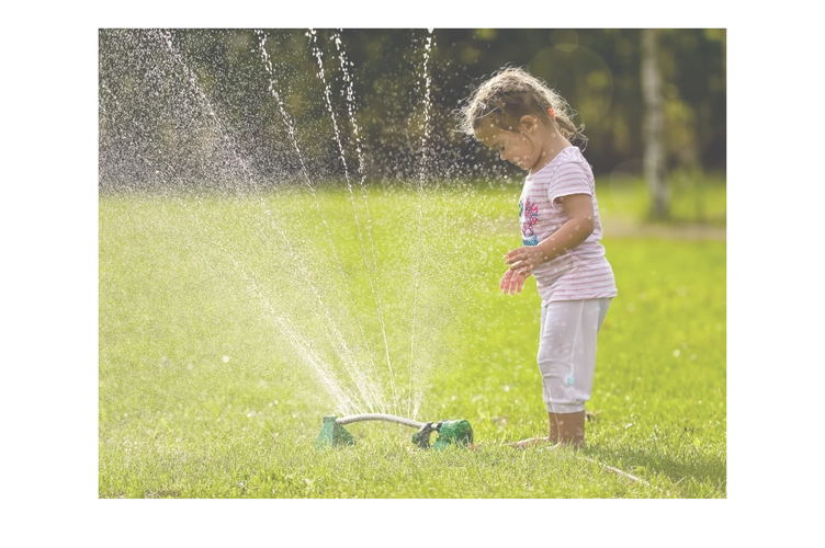 A young girl playing with a sprinkler.