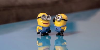 Two minion figurines standing on a reflective surface facing each other.