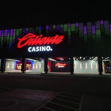 Brightly lit Caliente Casino entrance at night with neon signage.