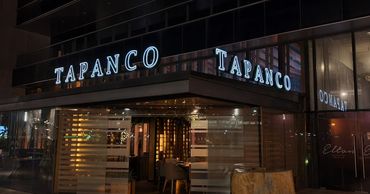 Exterior view of Tapanco restaurant at night with illuminated signs.