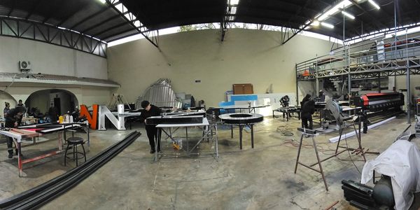 Wide view of a spacious workshop with various tools and workers actively fabricating materials.