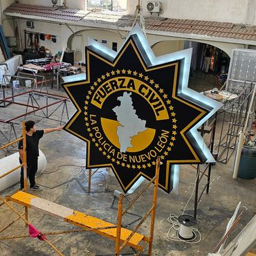 Large illuminated sign for Fuerza Civil police of Nuevo León in a workshop.