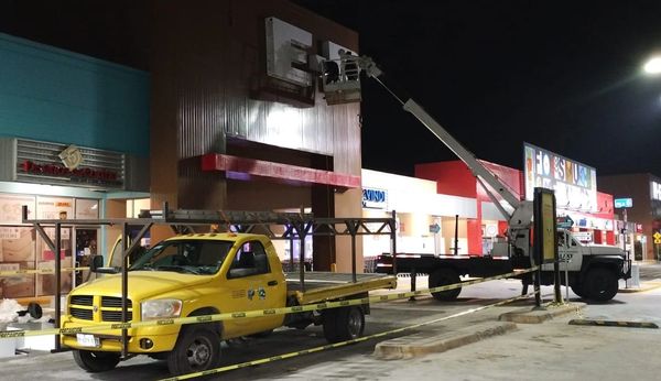 Yellow truck and white crane working on a sign at night.