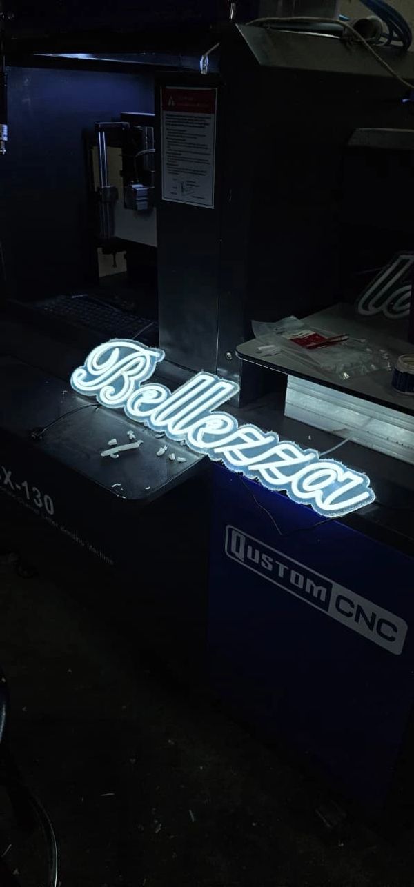 Illuminated neon sign reading 'Bellezza' on a Qustom CNC machine.