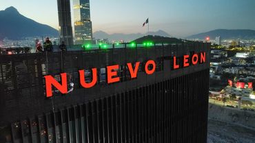 Illuminated Nuevo Leon sign on a skyscraper at dusk.