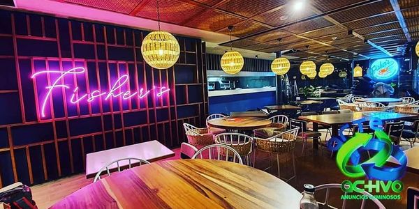 Cozy restaurant interior with wooden tables, wicker chairs, and warm lighting.