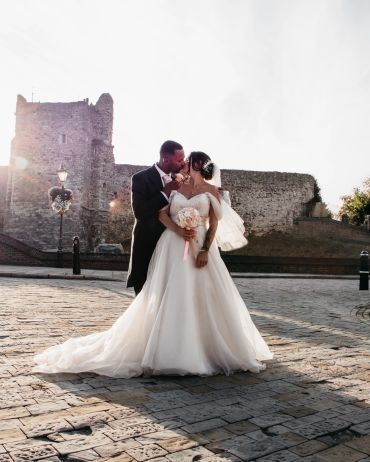 Bride and groom kissing in front of a castle.