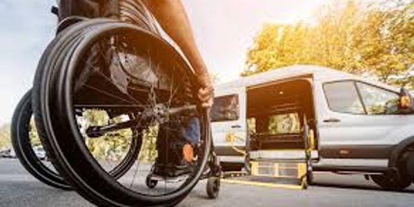 Person in wheelchair near accessible van with ramp.
