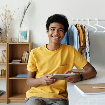 Smiling young man in a yellow t-shirt holding a tablet.