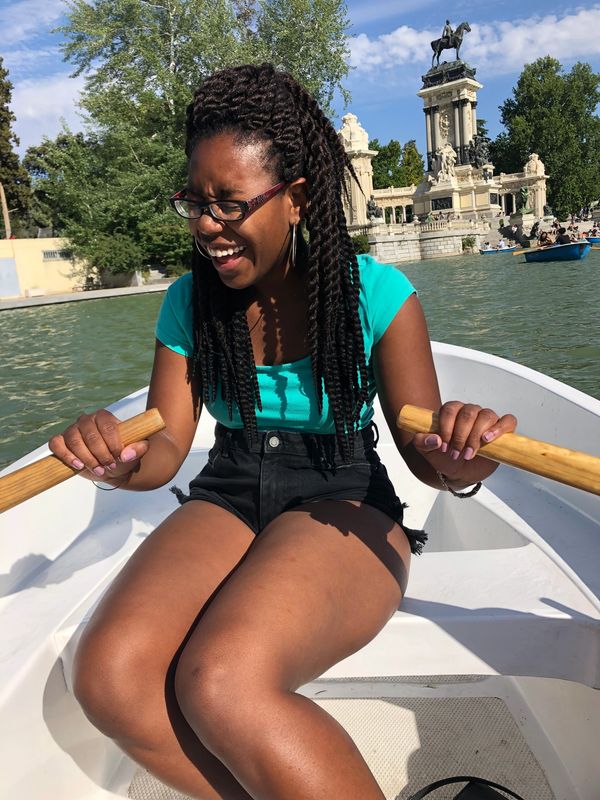 Woman laughing while rowing a boat on a sunny day.