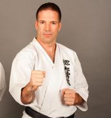 Man in karate uniform with clenched fists.