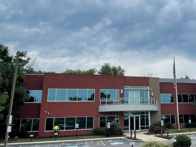 Modern two-story office building under cloudy sky.
