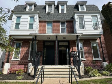 Exterior of a brick duplex house with a shared entry stairway.