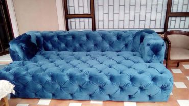 Luxurious blue velvet tufted sofa in a cozy room.