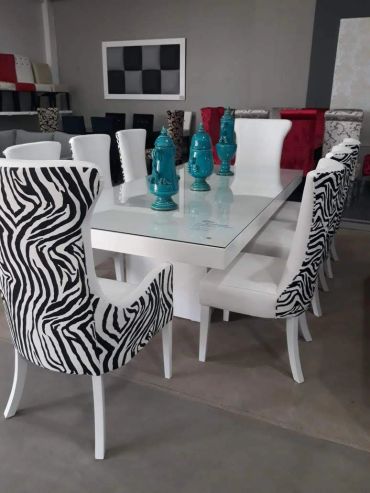 Modern white dining table with zebra-patterned chairs and turquoise decor.