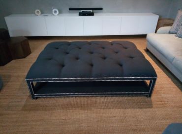 Modern tufted dark ottoman in a stylish living room.