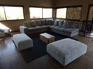 Modern living room with gray sectional sofa and ottomans on a dark rug.