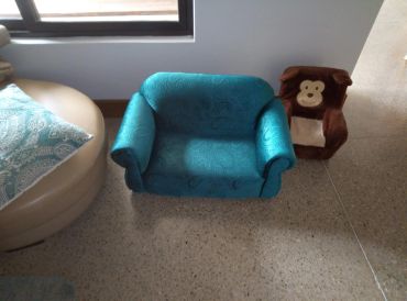 Two small chairs, one blue and one brown with a monkey design, placed on a tiled floor.