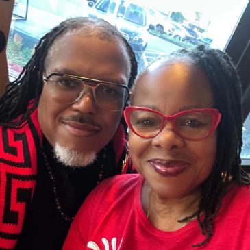 Two people smiling for a selfie indoors.