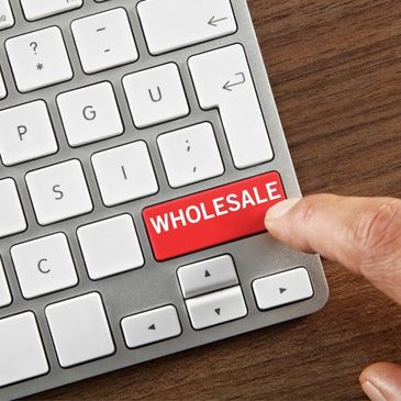 Finger pressing a red "WHOLESALE" key on a keyboard.