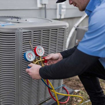 Technician checking an outdoor air conditioning unit with gauges.