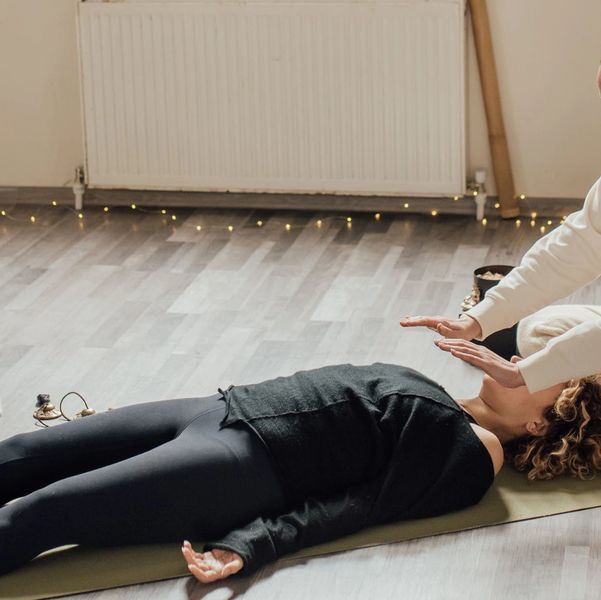 Person lying down with another giving energy work or healing.