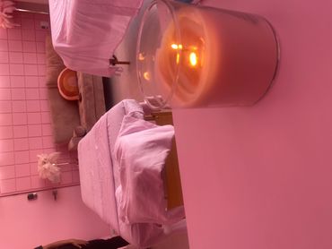 Cozy spa room with pink lighting and a burning candle.