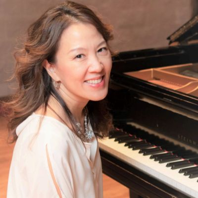 Woman smiling at the camera near a piano.