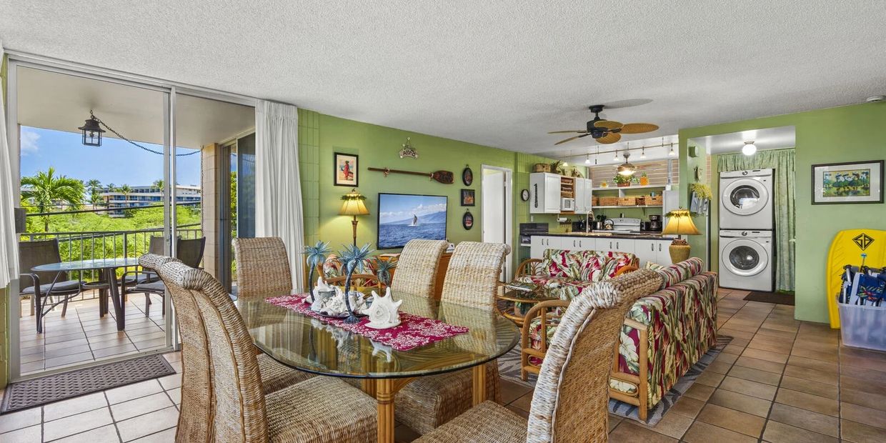 Bright tropical-themed living room with dining area and balcony.