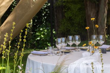 Mesa de jardín elegantemente puesta con copas y flores.