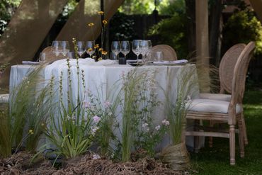 Mesa elegante al aire libre con decoración floral.