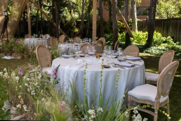 Mesa elegante preparada para evento al aire libre en jardín.