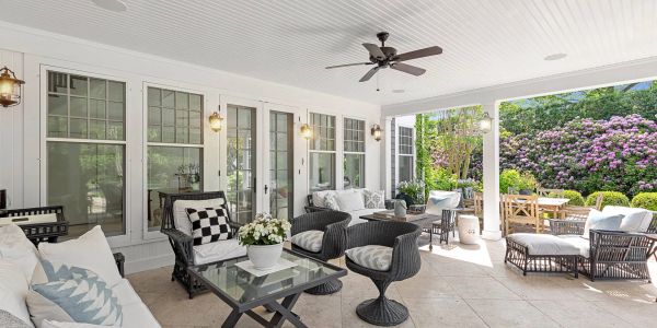 Bright and airy covered patio with comfortable seating and garden views.