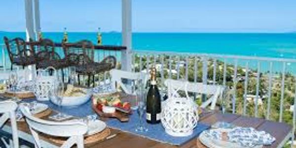 Elegant outdoor dining setup with ocean view and blue sky.