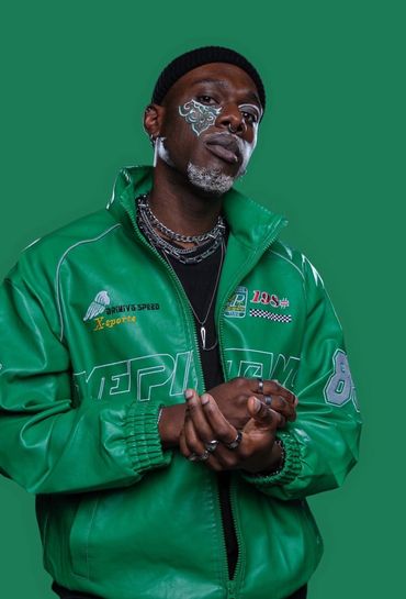 An African American man wearing a green racing jacket posing in front of a green background