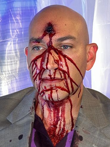 A man with a gunshot wound to the forehead using special effects makeup