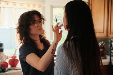 A photo of a women doing another women's makeup 