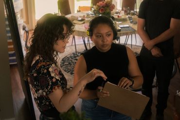 A photo of two women talking, one pointing and contemplating 