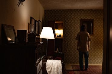 A woman in a dimly lit room standing in front of a mirror looking at herself. 