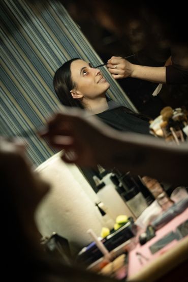 Photo of a girl getting her makeup done in the mirror