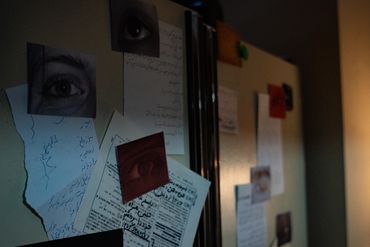 A photo of papers and pictures of human eyes hanging on a fridge