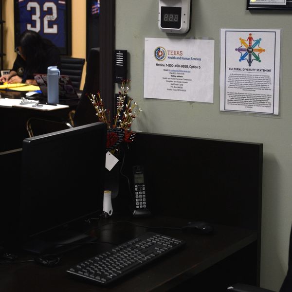 Office workspace with computer, keyboard, phone, and Texas Health and Human Services notice.
