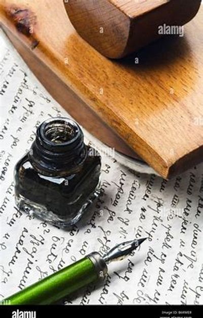 Vintage ink bottle and green fountain pen on handwritten paper.