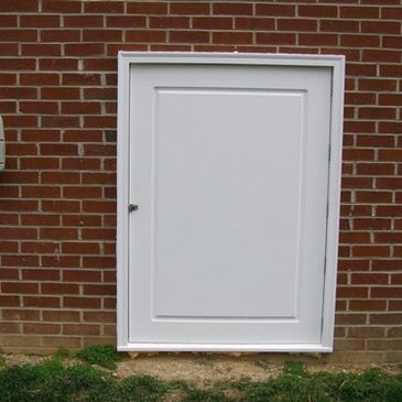 Small white door on a brick wall near a mailbox.