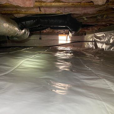 Plastic-covered crawl space with insulation and ductwork.