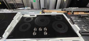 A black glass electric cooktop with five burners and control knobs.