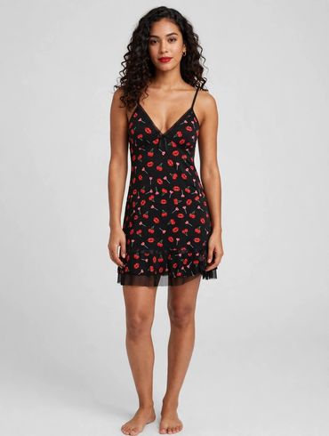 Woman in black mini dress with red floral pattern.