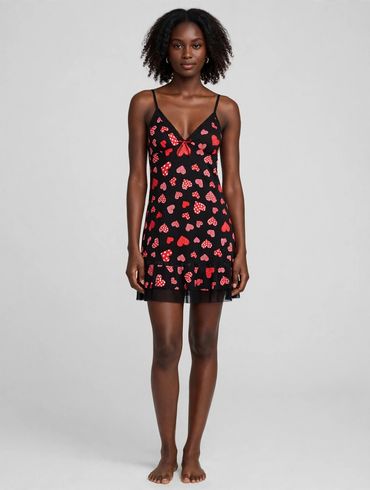 Woman wearing a black dress with red heart patterns.