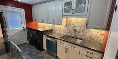 Modern laundry room with washer, dryer, and white cabinetry.